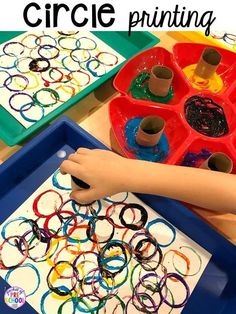 a child's hand painting circles on a tray with crayons and glue