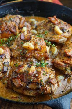 a skillet filled with meat and potatoes on top of a wooden table