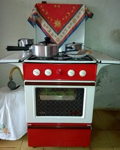 a red and white stove top oven sitting inside of a kitchen