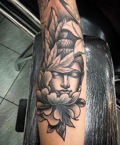 a woman's arm with a flower and buddha face tattoo on the left forearm