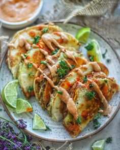 some tacos are on a plate with lime wedges and garnishes