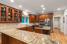 a large kitchen with granite counter tops and wooden cabinets, along with stainless steel appliances