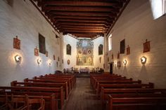 an empty church with wooden pews and stained glass windows on the wall above them