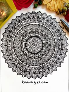 an intricate design is shown on top of a piece of paper next to some flowers