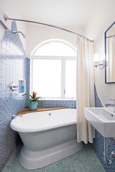 a bath tub sitting under a bathroom window next to a sink