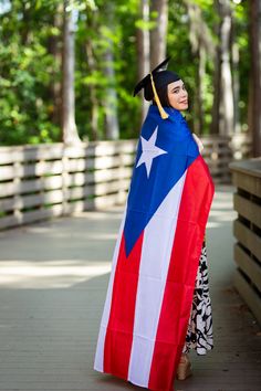 a woman wearing a graduation cap and gown holding a large puerto flag in front of her face