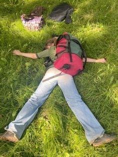 a person laying in the grass with a backpack on their back