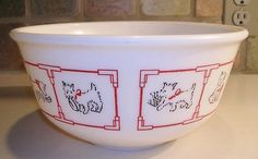 a white bowl with red designs on it sitting on top of a counter next to a brick wall