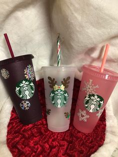 three starbucks cups with christmas decorations on them and one has a straw in the cup