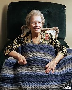 an older woman sitting in a chair with a crocheted blanket