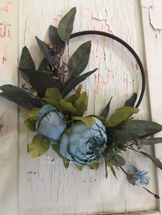 a headband with flowers and greenery is hanging on a door handle in the shape of a circle