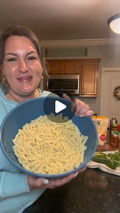 a woman holding a bowl of pasta in her hands