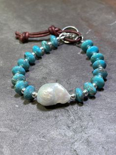 "Exquisite 10mm AAA Kingman Turquoise paired with sterling silver beads and featuring 1 AAA Baroque Pearl. Finished with a handmade Hill Tribe Silver button and leather loop to close at approximately 7\" and 8\". Will fit wrists 6.5\" - 7.5\". **Please note that due to the one of a kind nature of these large Baroque Pearls, each bracelet may differ slightly in composition but will contain the exact same materials as shown. Your turquoise beauty will arrive in my signature logo box, ready for gif Handmade Turquoise Pearl Bracelet With Round Beads, Handmade Adjustable Turquoise Pearl Bracelet, Bohemian Turquoise Pearl Bracelet With Round Beads, Hill Tribe Silver, Kingman Turquoise, Silver Buttons, Belfast, Baroque Pearls, Sterling Silver Bead