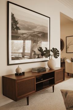 a living room with a large painting hanging on the wall and a wooden entertainment center