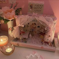 there is a doll house on the table with candles and flowers in front of it