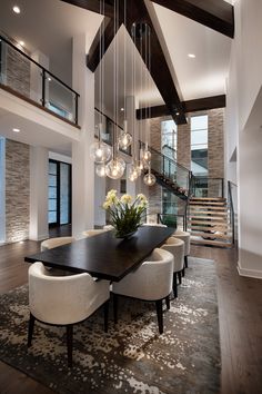 a dining room table with white chairs and chandelier hanging from it's ceiling