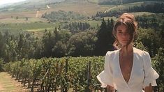 a woman is standing in the middle of a vineyard