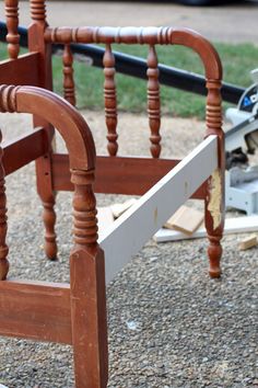 a wooden bed frame sitting on top of a gravel ground