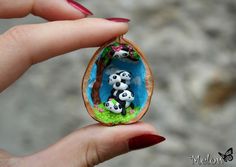 a woman's hand holding a miniature panda family