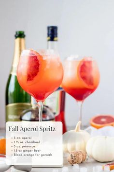 two wine glasses filled with pink grapefruit and garnished with orange peels