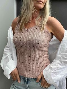 a woman with blonde hair wearing a pink sweater and jeans is posing for the camera