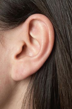 a woman's ear is shown with the top part of her head in view