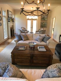 a living room filled with furniture and a chandelier hanging over the top of it