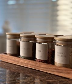 five jars with labels on them sitting on a counter