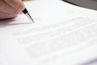 a person holding a pen and writing on top of a piece of paper