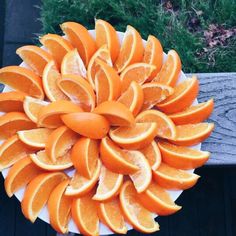 orange slices arranged on top of each other in a white plate with wood planks