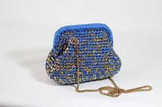 a blue and gold purse sitting on top of a white table next to a chain