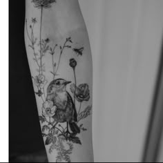 a black and white photo of a bird on a branch with flowers in it's arm