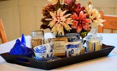 there is a tray that has some flowers in it on top of a table with blue and white dishes