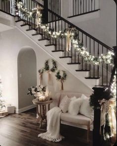 the stairs are decorated with christmas lights and garlands, while the couch is under the banister