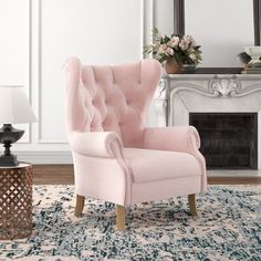 a pink chair sitting on top of a rug in front of a mirror and fireplace