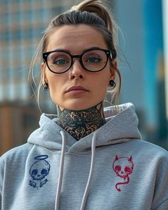 a woman with tattoos on her neck wearing glasses and a hoodie sweatshirt is looking at the camera