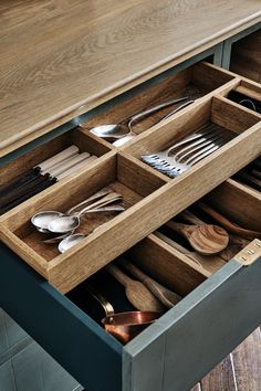 an open drawer with utensils and spoons in it