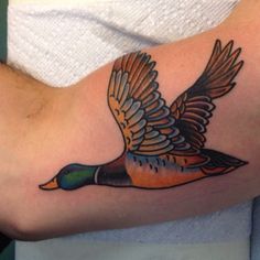 a tattoo on the arm of a man with a duck in it's wings