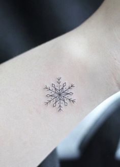 a small snowflake tattoo on the back of a woman's left arm