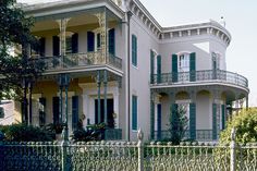 a large white house with green shutters and balconies