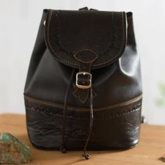 Handcrafted from leather in a solid black hue this backpack by Peruvian artisan Kathiana Quispe will make the perfect companion on your journeys. Pyramid patterns are embossed around the backpack and on its flap and the image of two mountains is imprinted onto the front. Opening with a belt buckle drawstring and zipper this bag reveals a roomy single-compartment lined interior for storing your belongings. This accessory drapes over the shoulders on two adjustable straps. Handmade Black Backpack For Travel, Handmade Black Travel Backpack, Handmade Leather Backpack For Daily Use, Artisan Backpack For Daily Use, Peru Machu Picchu, Imperial Leather, Tooled Leather Handbags, Vacation Bag, Favorite Purse