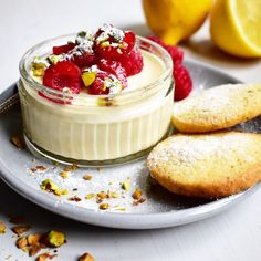 a dessert with raspberries and cookies on a plate next to some lemons