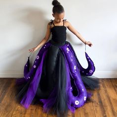 a woman in a black and purple dress with an octopus tail on her head, holding a pair of scissors