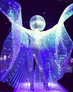 a woman is dressed up as an angel in front of a mirror ball and disco balls