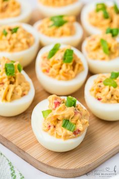 deviled eggs with mayonnaise and green garnish on a cutting board