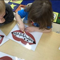 two children sitting at a table working on their art project with paper and pencils