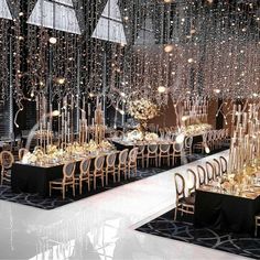 a room filled with lots of tables covered in gold and black chairs next to tall chandeliers