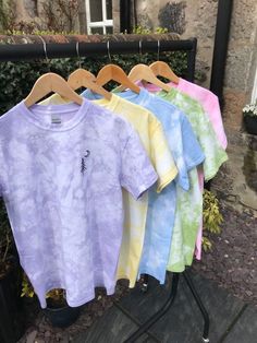 four t - shirts hanging on a clothes rack outside