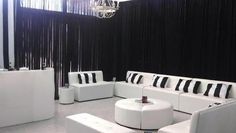 a living room with white couches and black drapes on the wall behind them