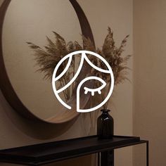 a round mirror sitting on top of a wall next to a vase